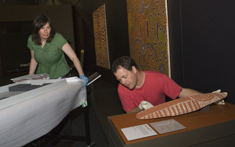 Karen Peterson guides a trolley past a plinth where Tim Moore is placing a wooden shield.