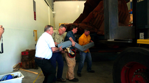 Staff members attach one of the wheels to the cradle support.
