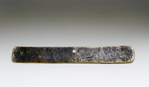 Back view of the Leichhardt nameplate. The greyish-brown surface of the nameplate appears uneven and there are two score marks at the bottom close to the centre and a fastening hole at the top in the centre.