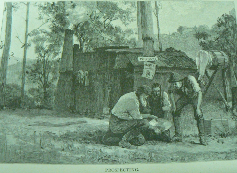 Three miners outside a shack peering at a gold pan.