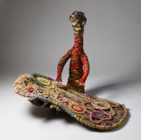 Aboriginal person with painting A sculpture depicting a person working on a painting. The sculpture is made of woven grass, plant material dyed in different colours and strands of wool.
