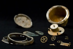 Metallic casing and inner workings of clock with broken glass face.