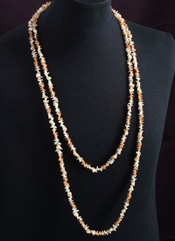 A necklace made from sea shells displayed on a dressmaker's dummy.