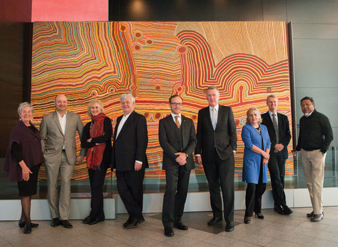 Council members standing in front of a large Aboriginal painting, from left: Barbara Piscitelli AM, Nicholas Davie, Andrea Hull AO, John Morse AM, Andrew Sayers AM, Daniel Gilbert AM, Rae Francis, David Jones, Peter Yu.