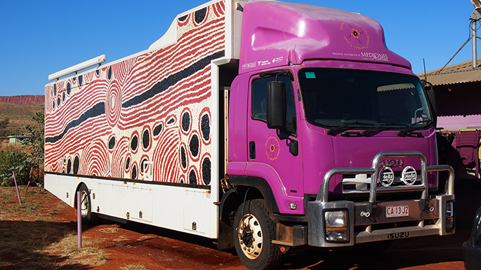 A large purple truck with Indigenous artwork on its side.