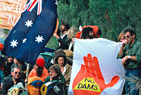 Franklin Dam and the Greens Young people squatting or standing on a dirt road holding the Australian flag and various banners.