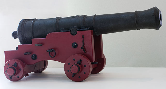 iron cannon on a red painted wooden base with four wheels