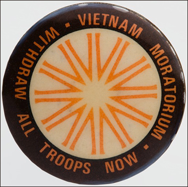 White, black and orange badge with the words Vietnam Moratorium/withdraw all troops now around the rim.