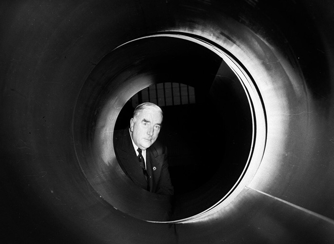 a black and white photo of an older man looking through a tunnel