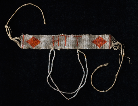 A glass beaded armband with the Elsey cattle brand 'HTT' in red and a red diamond at both ends.