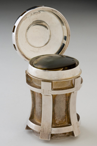 Captain James Cook's magnifier. A silver presentation case in the shape of a ship's capstan. There is an oval well inside the case, which accommodates the magnifying hand-lens.