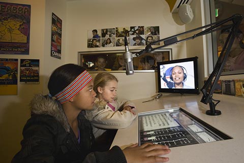 Two young visitors seated at the radio control panels in the studio