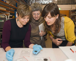 Three women looking at small coin.