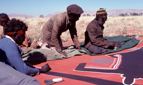 Men working on a painting in the desert.