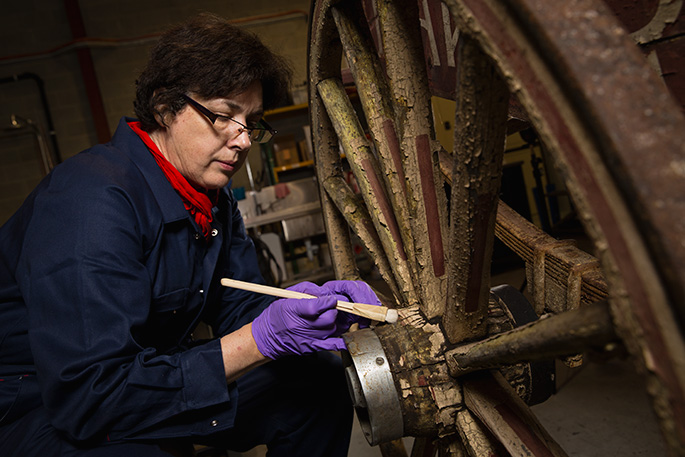 Conservator Kathryn Ferguson treating a 1930s bakery cart for display in Spirited: Australia’s Horse Story