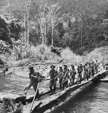 About 20 soldiers use a simple bridge that is little more than a pair of logs.