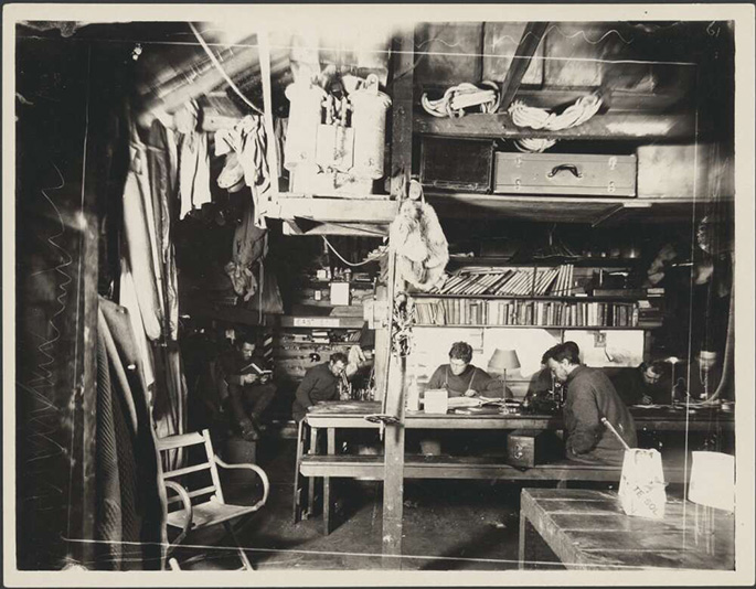 black and white photo of men inside hut