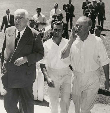 Menzies in suit and Dexter and Bradman in cricket whites to his left