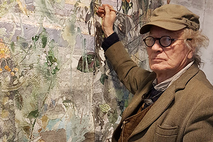 an older man dressed in a brown suit with matching cap and wearing spectacles is holding a paint palate in one hand and a paint brush in the other. He looks as if he is putting the finishing touches on a large painting attached to the wall.