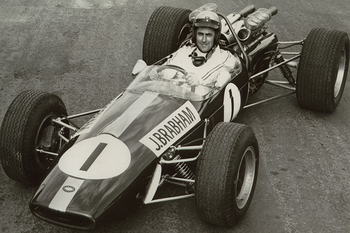 a black and white photo of a man sitting in a racing car