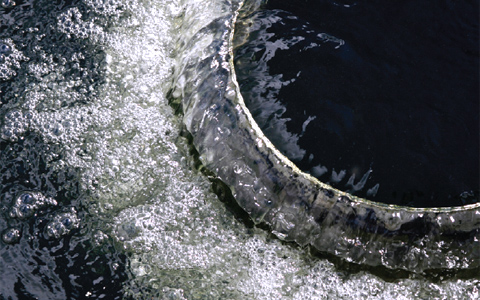 Close-up looking down at water spilling and bubbling over a circular feature.