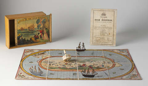 A hand-coloured lithographic playing board made of eight paper sections mounted on linen, with a polygonal twelve-sided teetotum or spinning dice and three small painted metal playing pieces in the shape of tall ships. A varnished wooden box and an instruction sheet have been placed beside the game board.