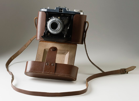 A black camera housed in a brown leather case.