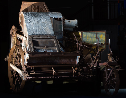 Wood-framed harvester with comb at front and 'Sunshine' stamped in metal at the top