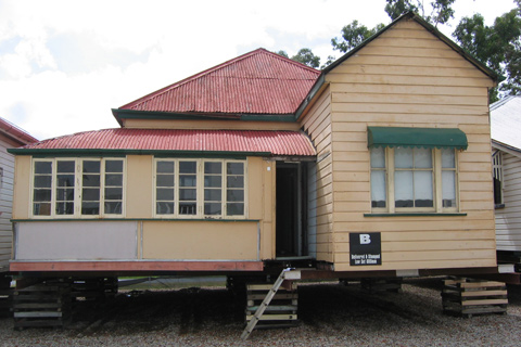 Timber house with a red, corrugated iron roof, raised on wooden supports