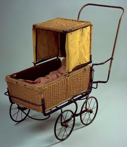 A folding pram (perambulator) with a metal frame and woven wicker body and hood that has separate canvas flaps attached to the left and right side, 1930s.