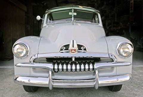 Front view of a light grey Holden sedan with a silver grille and bumper and round headlights.