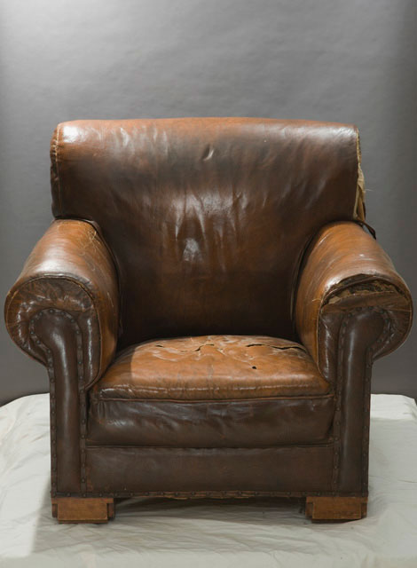The chair before conservation treatment showing damage to the seat, arm rests and sides.
