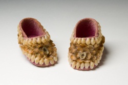 Small pink baby shoes decorated with yellow-brown shells.