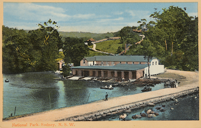 A coloured black and white photo of a building next a body of water with trees and grass in the background.