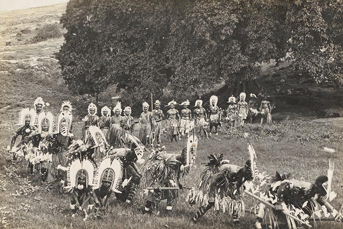 Procession of Torres Strait Islander dancers in elaborate traditional costumers.