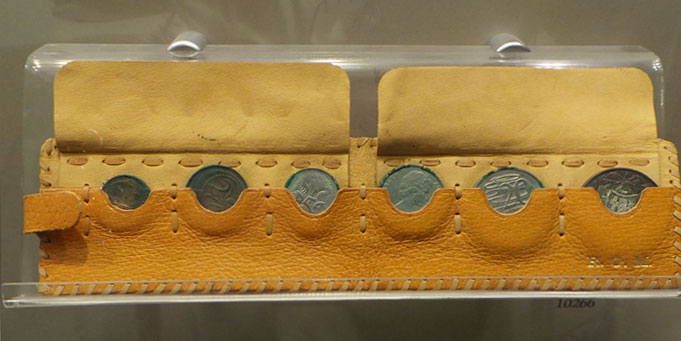 A yellow leather pouch containing six tarnished coins – the one, two, five, 10, 20 and 50-cent pieces. The initials R G M are embossed in gold.