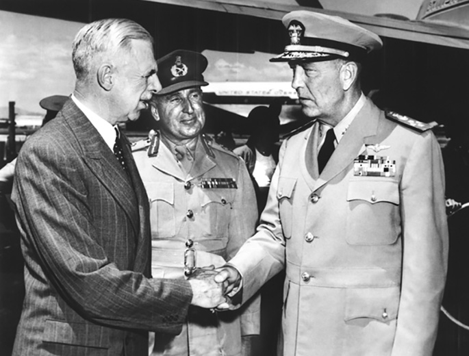 man in suit shakes hands with US admiral in uniform while New Zealand general looks on