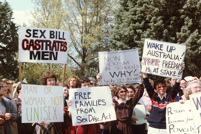 colour photo showing women and a couple of men protesting. Many are holding placards saying things like ‘Sex bill castrates men’, ‘Free families from Sex Disc Act’, ‘Wake up Australia! Your freedom is at stake’