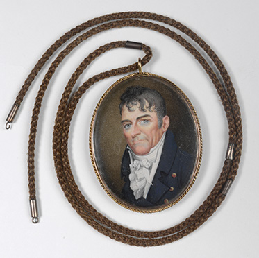 miniature portrait with necklace attached. The portrait depicts a man wearing a blue coat and a flouncy cravat. He has blue eyes and black wavy hair.