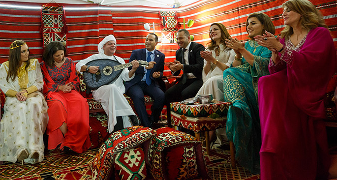 A group of women and men dressed in cultural costumes sing and play music
