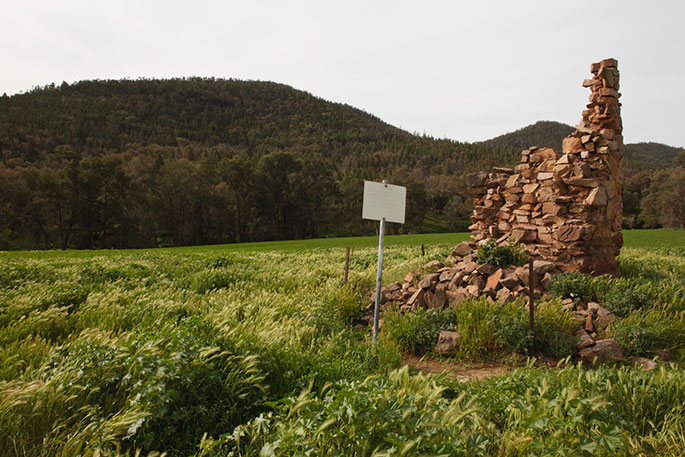 Remains of a stone building in a green field.
