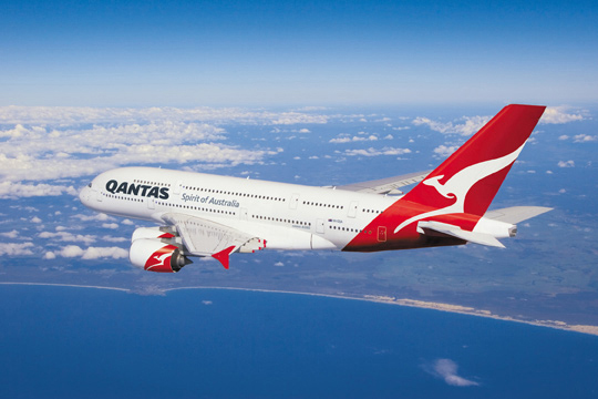 Qantas aircraft in flight over coastline.