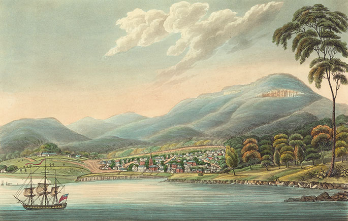Colour picture showing a small town on the edge of a harbour. A ship is in the foreground; hills are in the background