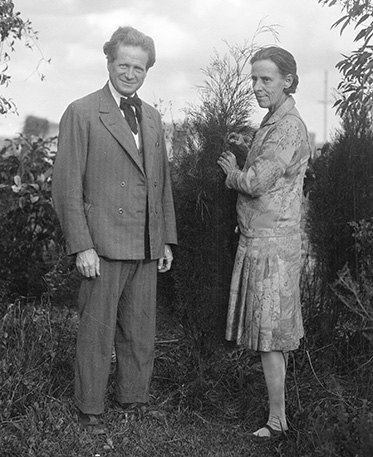 An old black and white photo of a middle-aged couple outdoors.