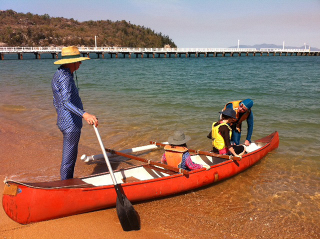 Canoe on the shore with four people.