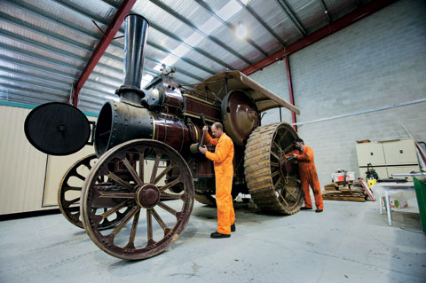 The Fowler steam engine towers over Peter Bucke and Ian Cramer as they perform maintenance work
