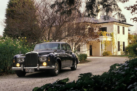 The Bentley car parked in the driveway of the two-storey Lodge building.