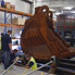 A smaller forklift attached to the bucket cradle with two long steel poles.