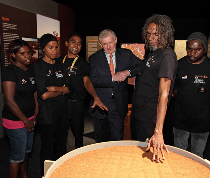 A group of people surrounding an object containing sand.