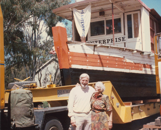 A colour photograph of John Robinson and his sister with the PS Enterprise in the background.